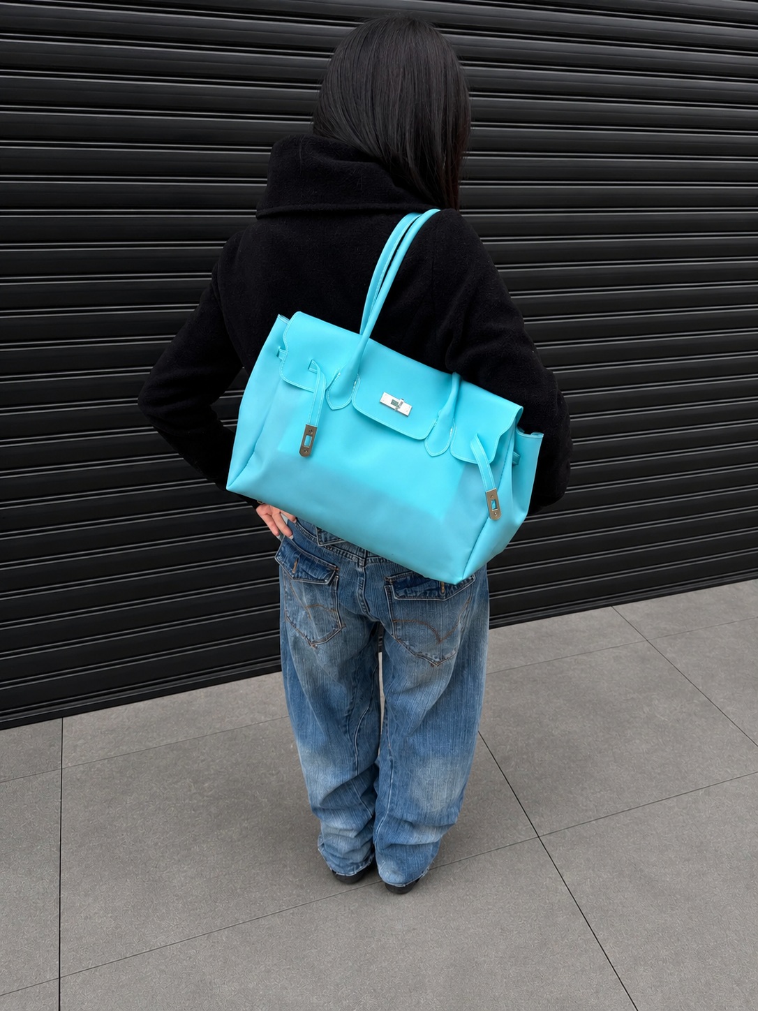 Mannequin de dos portant le sac Jelly Firkin Lagoon bleu turquoise à l'épaule, look casual en jean