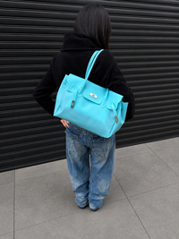 Mannequin de dos portant le sac Jelly Firkin Lagoon bleu turquoise à l'épaule, look casual en jean