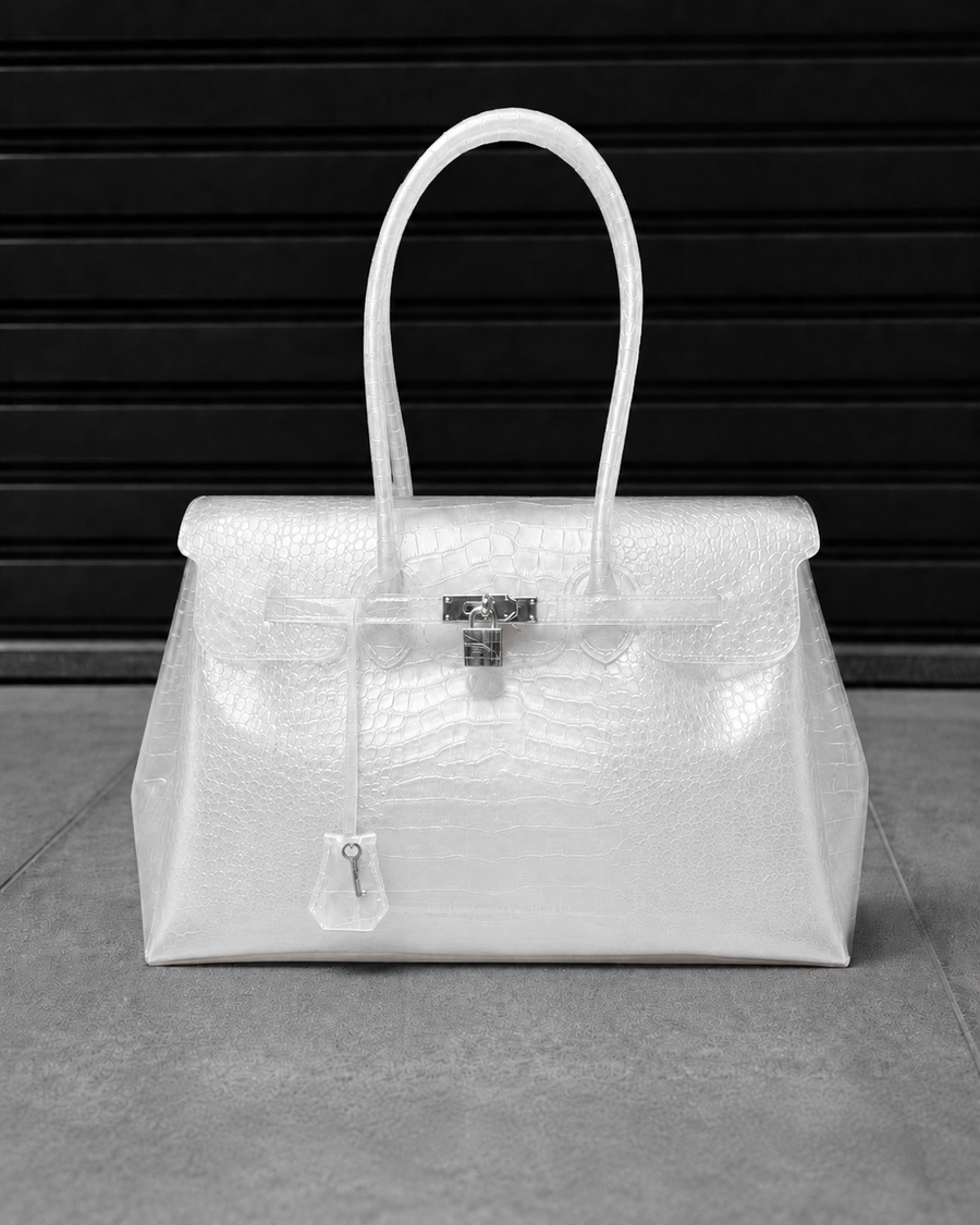Sac Jelly Firkin Croco Pearl blanc nacré effet croco posé au sol, vue studio devant un rideau métallique