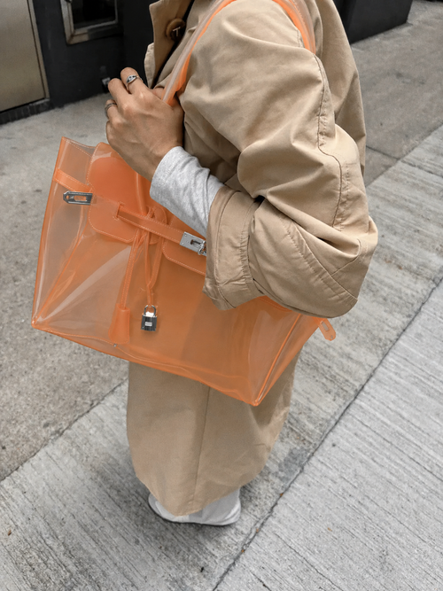 Mannequin portant le sac Jelly Firkin Sunset orange coucher de soleil au bras, look tenue beige oversize