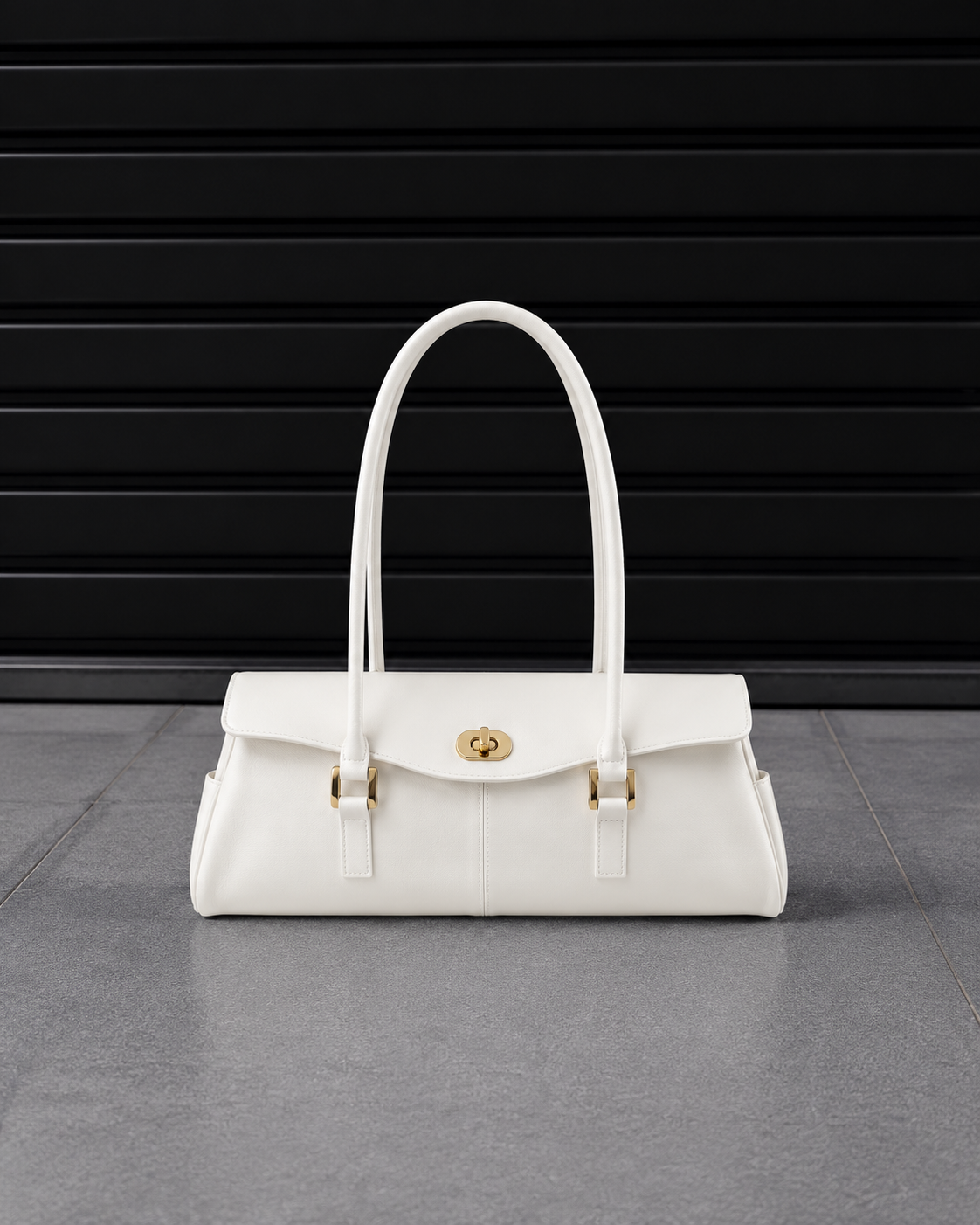 Sac baguette Jelly Firkin Pearl blanc nacré posé au sol, vue studio devant un rideau métallique noir