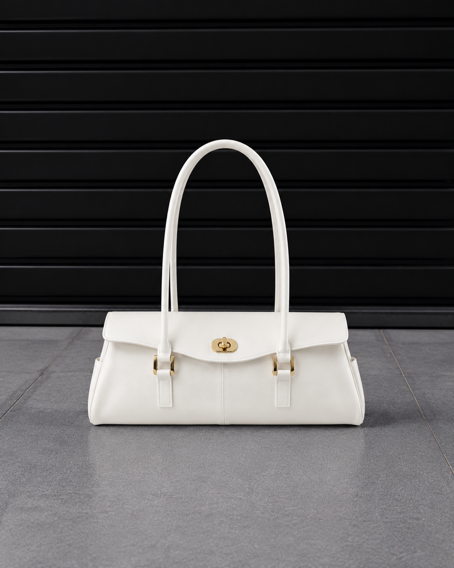 Sac baguette Jelly Firkin Pearl blanc nacré posé au sol, vue studio devant un rideau métallique noir