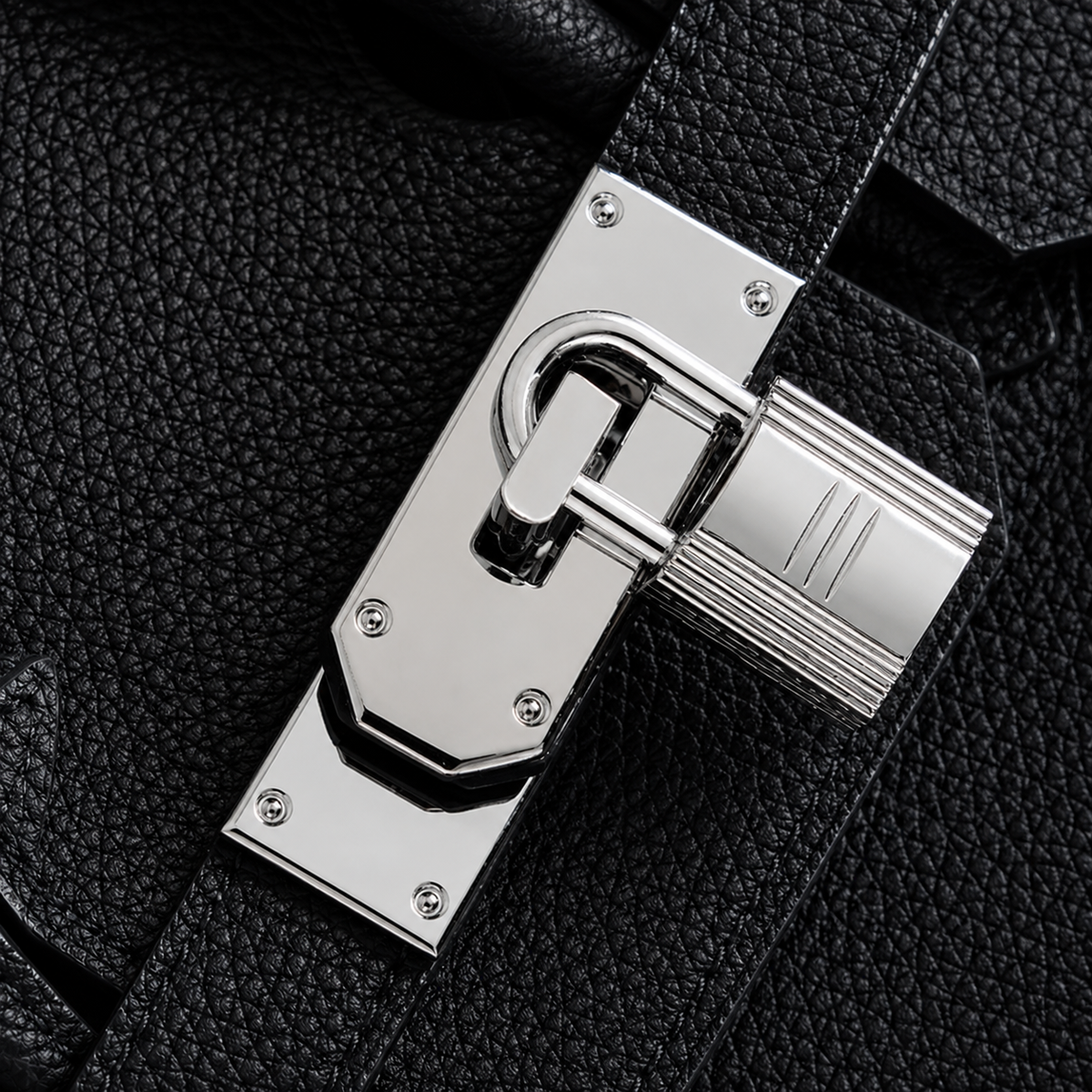 Gros plan sur le fermoir cadenas argenté du sac Elan Bag Ébène en cuir grainé