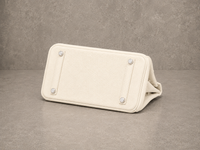 Dessous du sac Elan Bag Ivoire, base en cuir grainé blanc ivoire protégée par des pieds métalliques